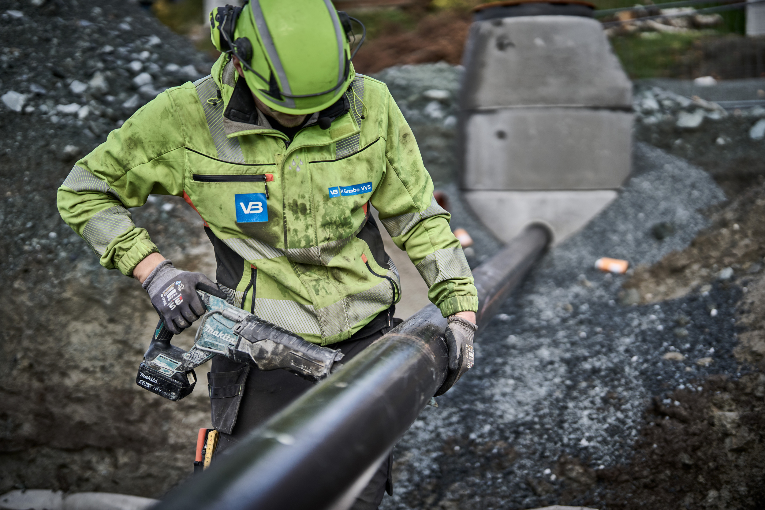 VB-rørlegger deler et rør mens han jobber i grøfta.